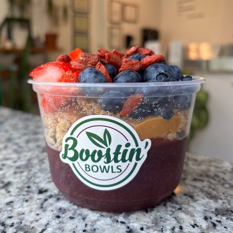 Purple bowl with granola, mixed berries, and peanut butter swirl
