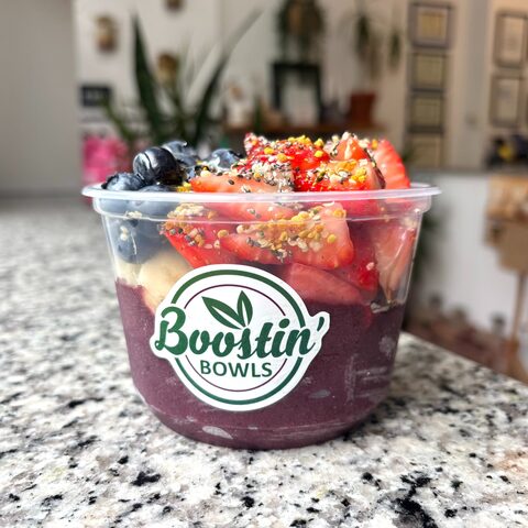 Purple bowl with granola, banana, berries, and seeds