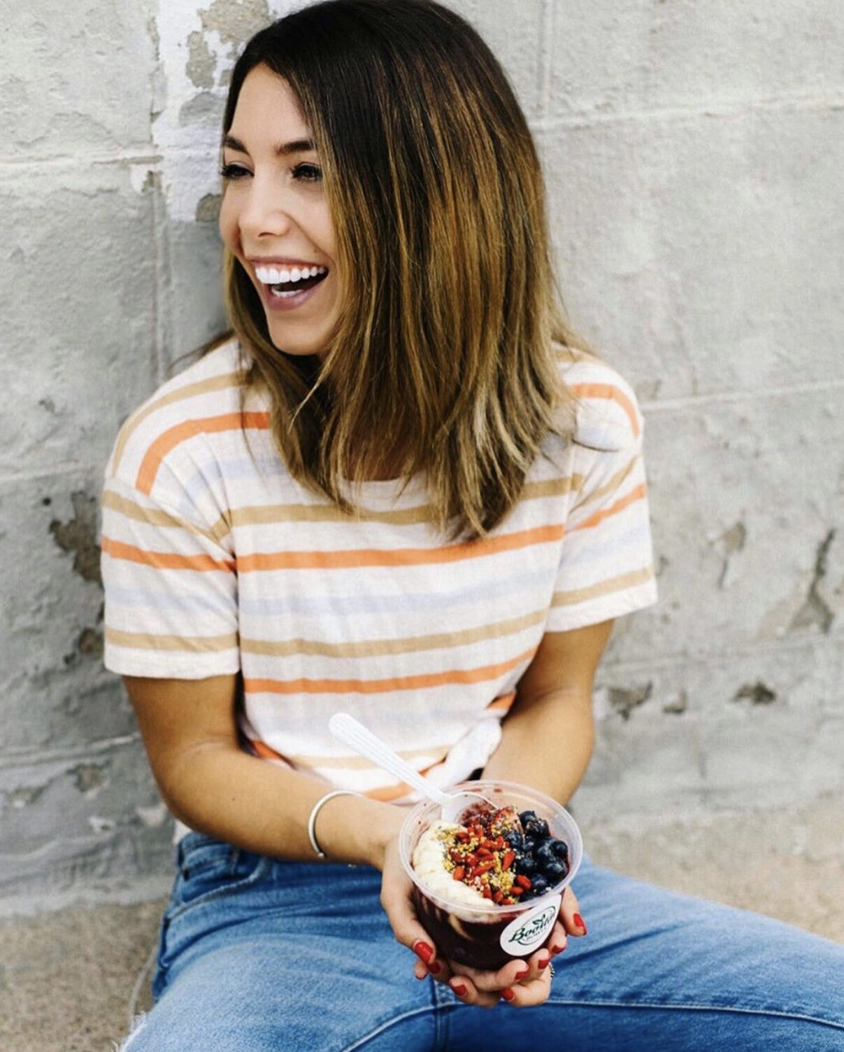 A customer laughing while holding an açaí bowl